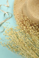 Dried flower bunch on blue background with hat and ribbon