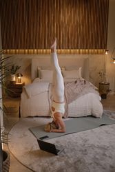 Young female practicing yoga in bedroom