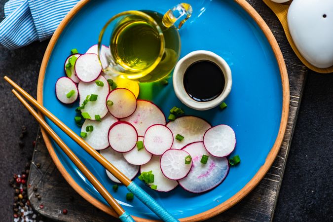 Top view of sliced fresh radishes on blue plate