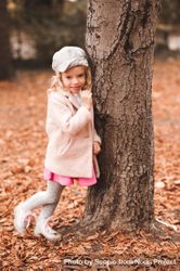 Young girl wearing pink jacket leaning on brown tree 4A8O65