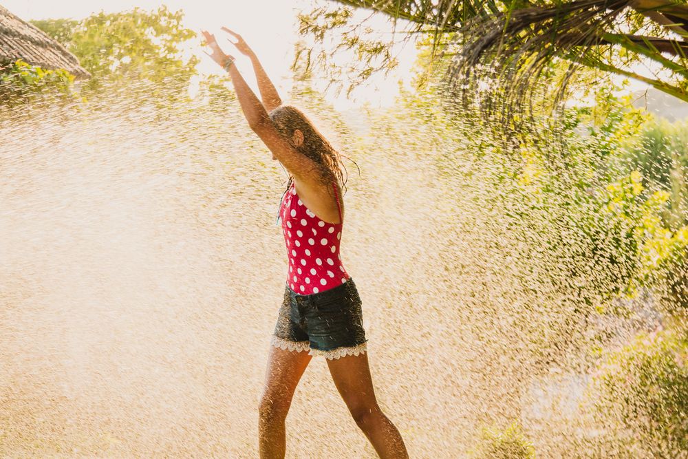 Cheerful teenager having fun with jet of water