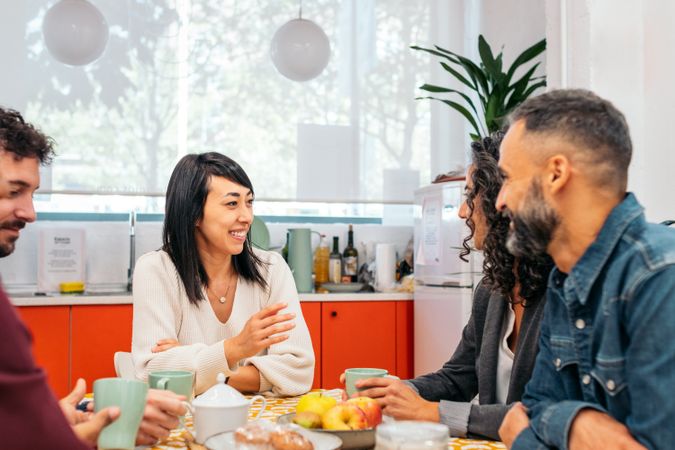 Coworkers eating happily in the kitchen of a coworking office during a break