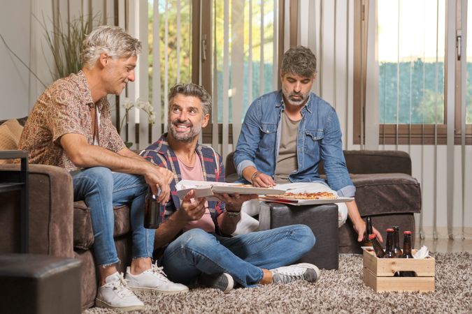 Group of friends chilling at home with beer and pizza