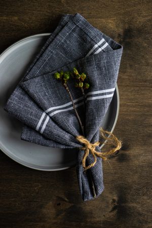 Rustic table setting with cherry blossom branch in napkin on wooden table