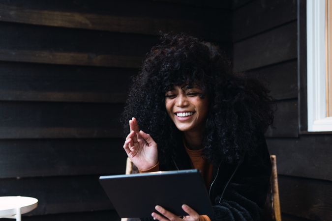 Smiling Black woman with tablet on veranda