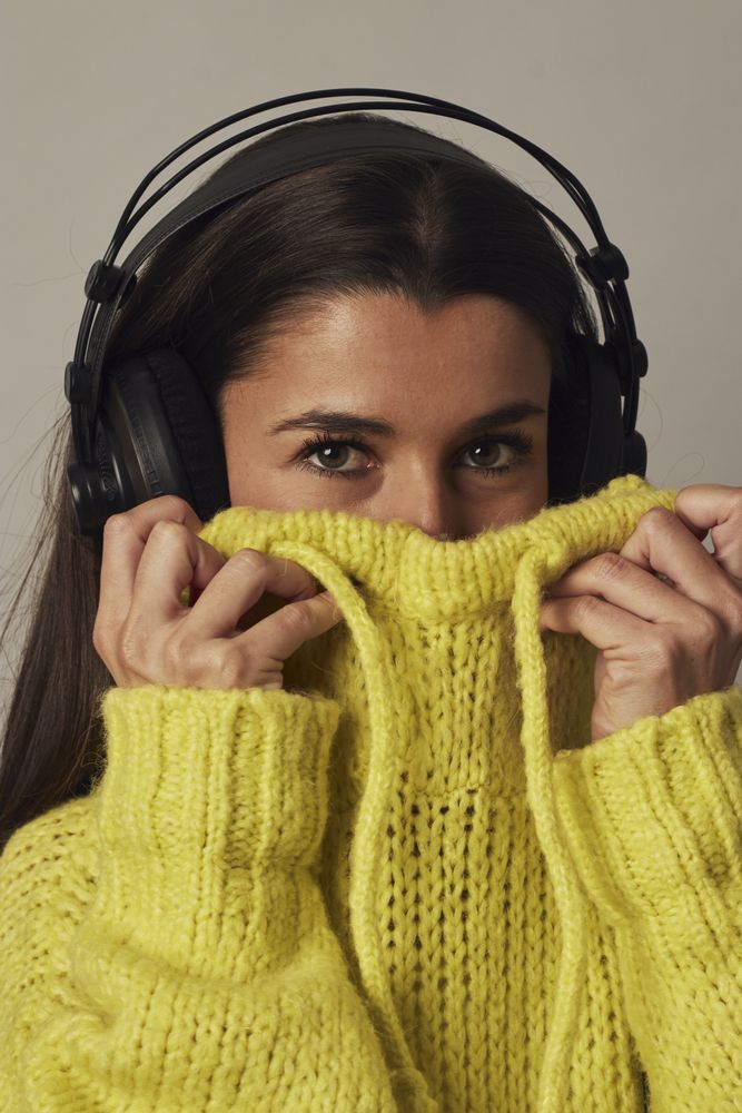 Playful young woman listening to music in studio