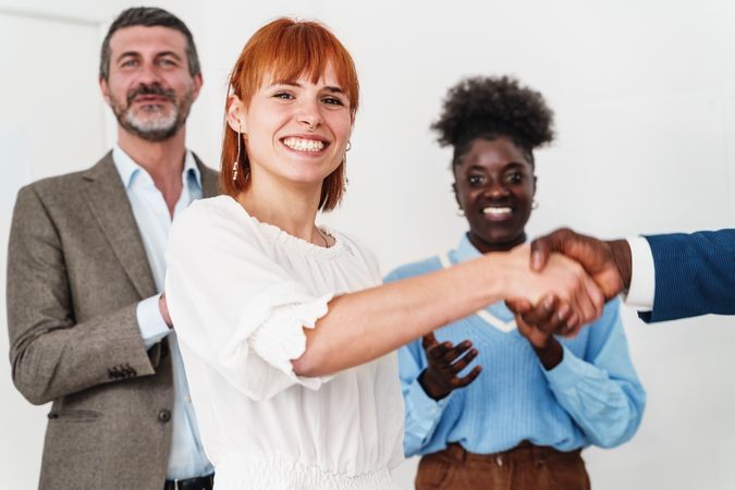 Portrait of a white woman shaking hands with a Black man in a professional office