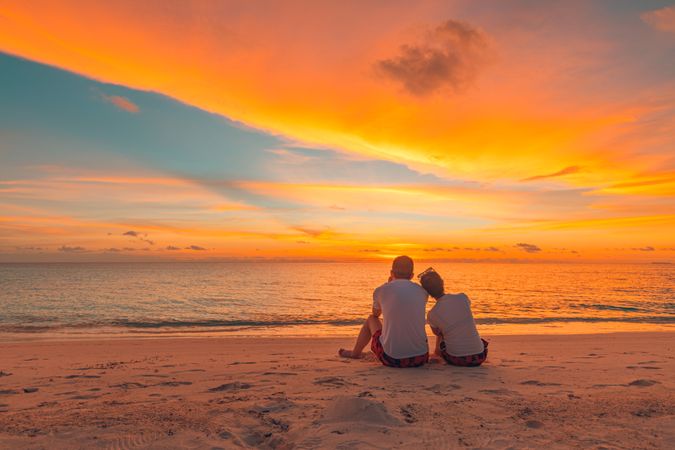 Two people looking out at the ocean on sunset