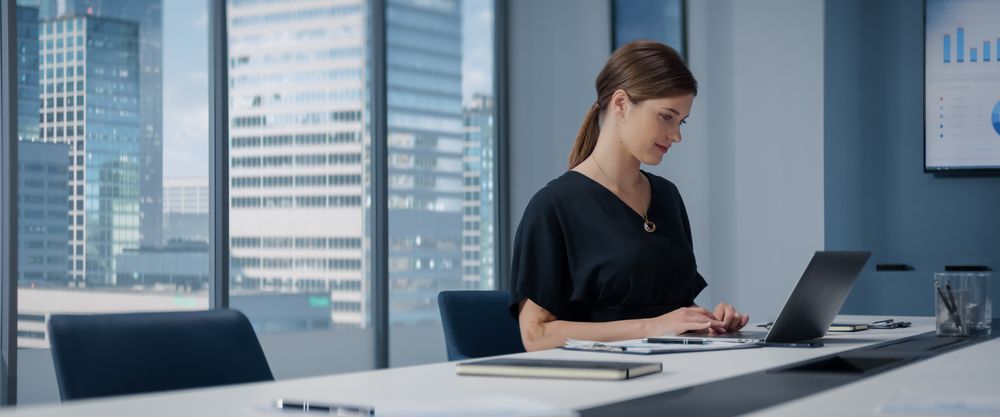 Portrait of Successful White Businesswoman Working on Laptop Computer in Big City Corner Office.