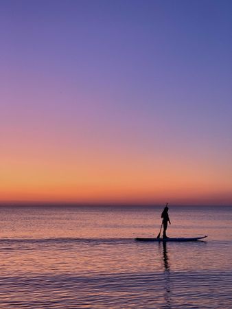 Silhouette of person kayaking in the sea during sunset