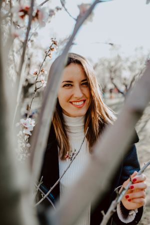 Young happy woman between trees in garden