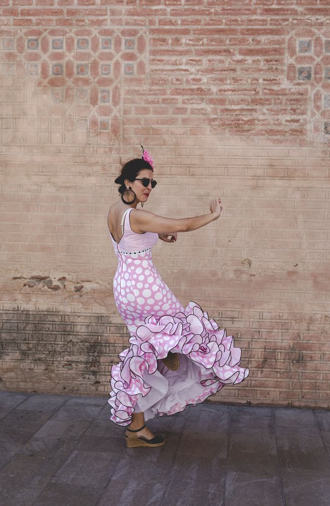 Passionate woman in flamenco dress dancing on street