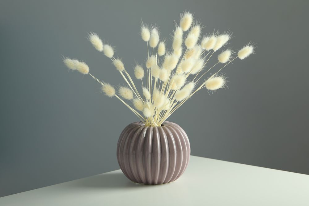 Round and ridged vase in grey room filled with dried flowers