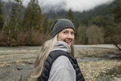 Smiling older woman looking back over her shoulder near mountain stream