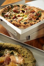 Italian pizza with basil and tomato served with cold beer on checkered tablecloth