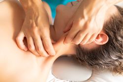 A physical therapist massages the sternocleidomastoid muscle in her patient's neck to decrease tension and pain