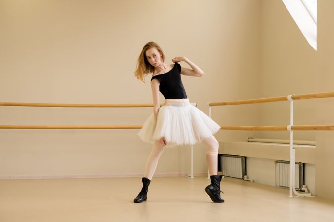 Ballerina in shoes and tutu, holding shoulder in modern dance