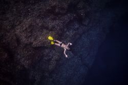 Unrecognizable man in flippers swimming under dark water