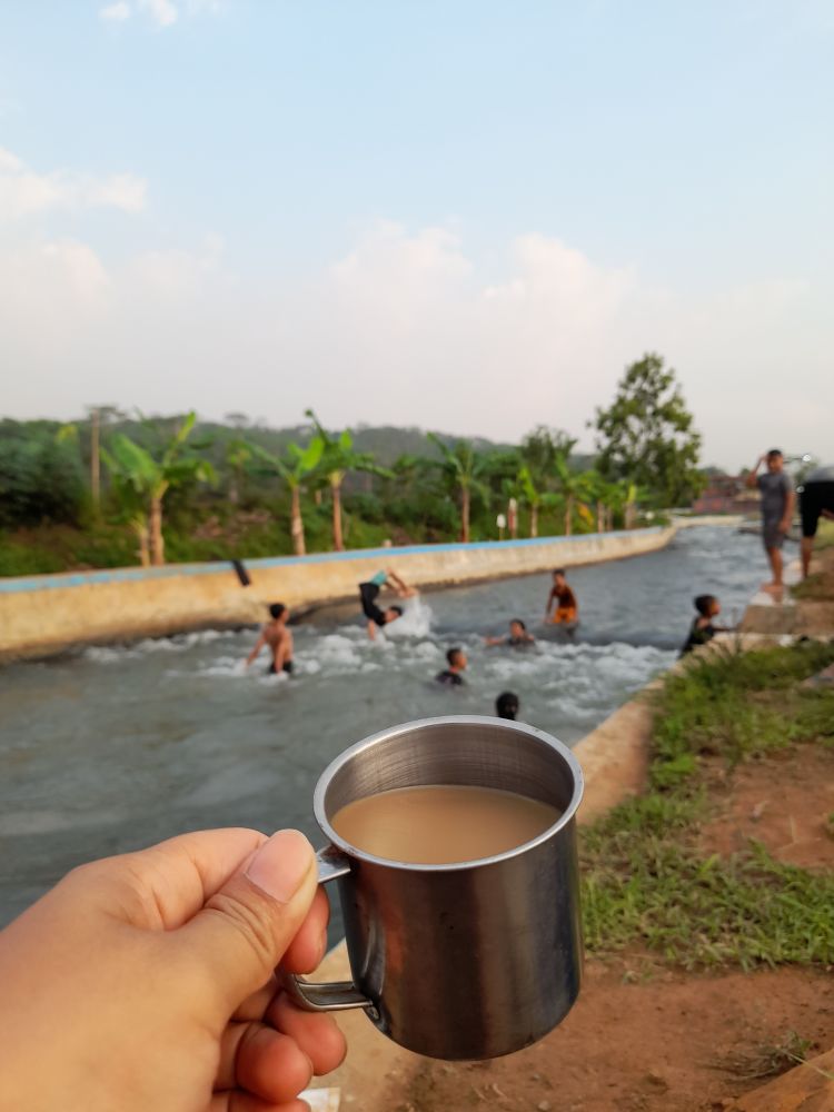 Enjoying a cup of coffee by the river while watching people swimming