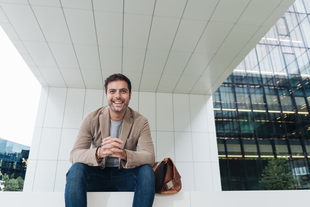 Cheerful manager sitting outside modern building