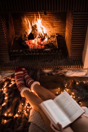 Crop legs with book near fireplace