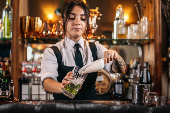Female bartender preparing a cocktail in a traditional cocktail bar