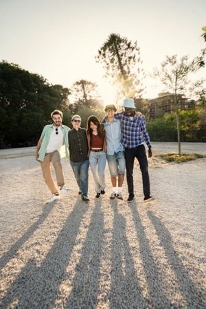 Diverse friends with long shadows walking outdoors with copy space in the sky.