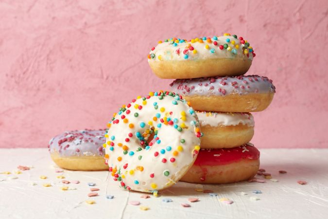 Tasty donuts on table against pink background