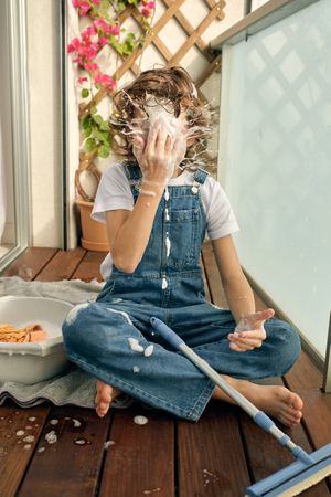 Boy splashing foam on face during balcony cleaning