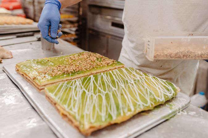 Crop baker spilling crumbs on cake