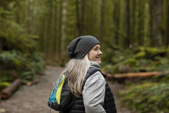 Profile view of woman smiling while on a break during a hike in the woods