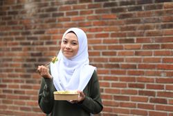 A Beautiful Asian Muslim Woman Wearing a Hijab Enjoys Eating Healthy Yummy Salad Bowl