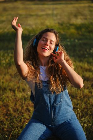 Joyful woman in headphones dancing in meadow