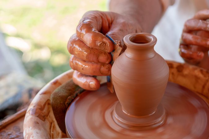 Person making clay pot during daytime