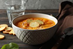 Bowl of warming pumpkin soup on table with glass of water