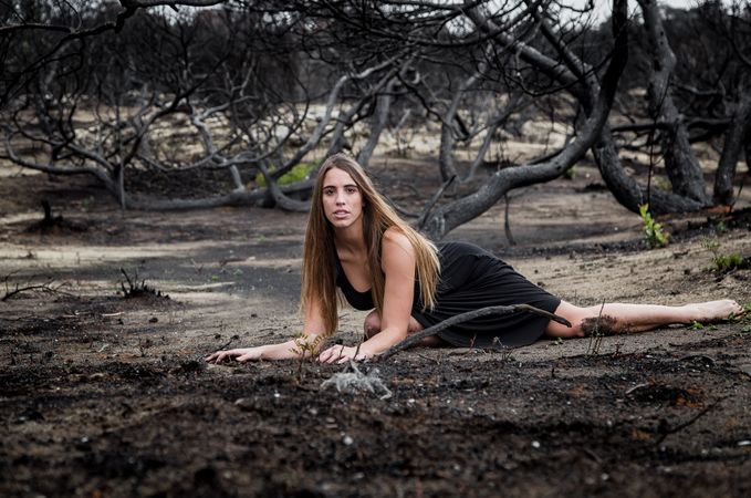 Woman posing on ground near dry trees