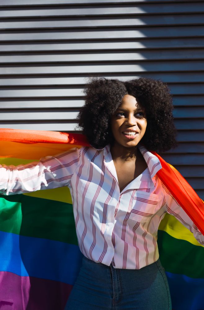 Fun Black woman posing happily with the LGBT flag