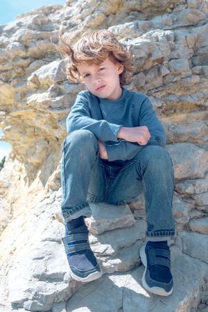 Calm boy sitting on cliff