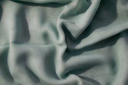 Nude green fabric wavy crumpled background texture with copy space.
