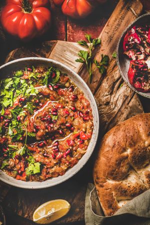 Eggplant dip with pomegranate and parsley garnish on wooden surface