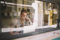 Man talking on smartphone while browsing laptop