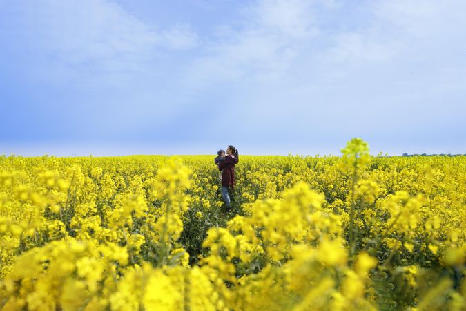 Woman holder her baby in the distance in yellow field