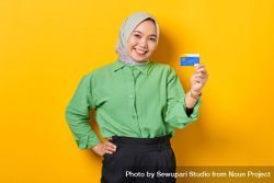 Smiling Muslim woman in headscarf and green blouse holding credit card 41LzL5