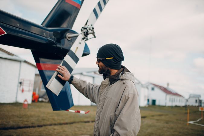 Man wearing knit cap touching airplane fan