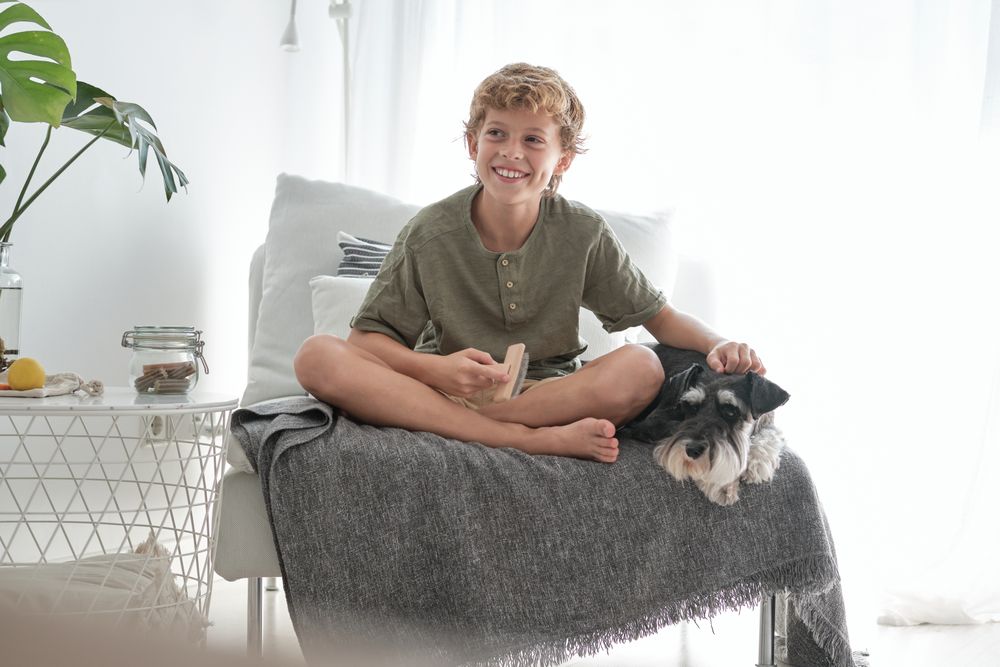 Smiling boy stroking purebred dog lying nearby