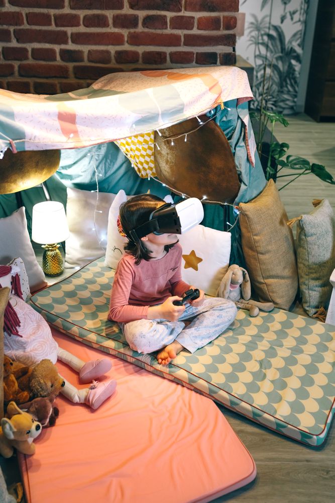 Digital native with virtual reality glasses watching 3D video sitting over mat in a tent at home