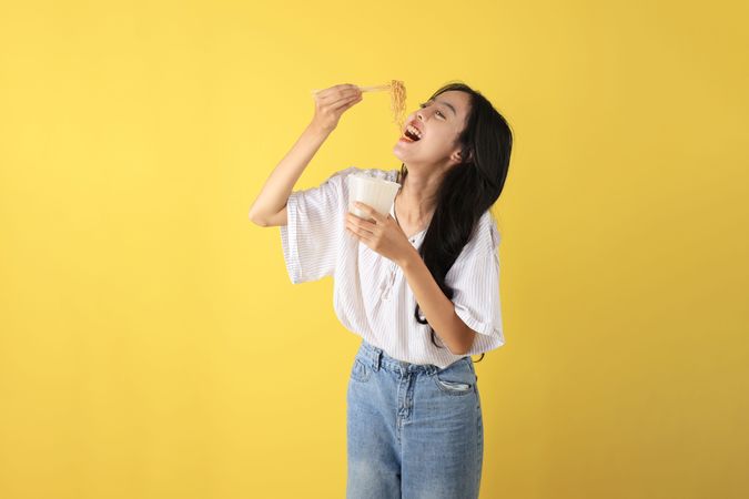 Young Indonesian Teenager Eating Instant Noodles using Chopstick.