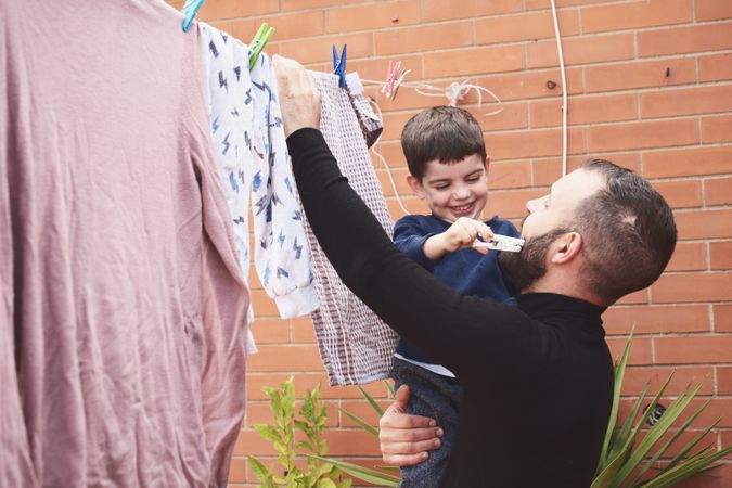 Father and son hanging clothes on rope
