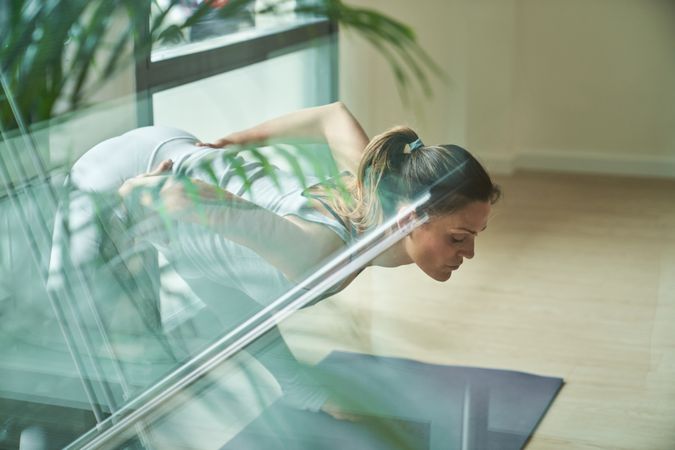 Woman in activewear taking Prasarita Padottasana B pose during yoga session