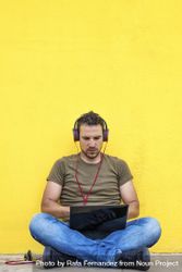 Male with red headphones sitting outside looking at laptop 0V3YG5